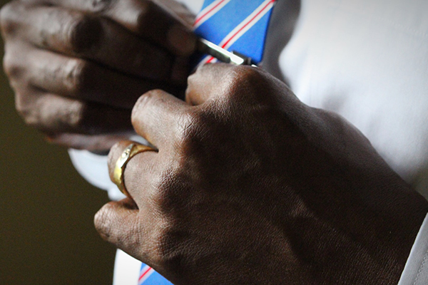 Black professional tying a tie