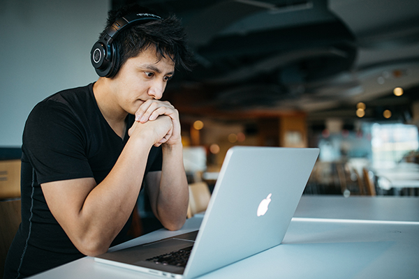 man working on laptop with headphones