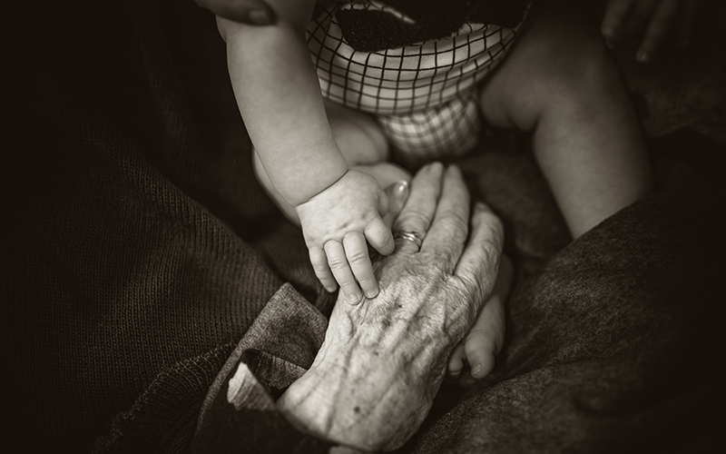 A baby touching an older person's hand