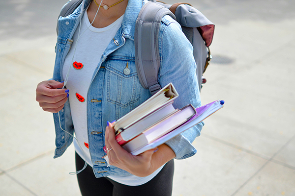 Woman with backpack holding books