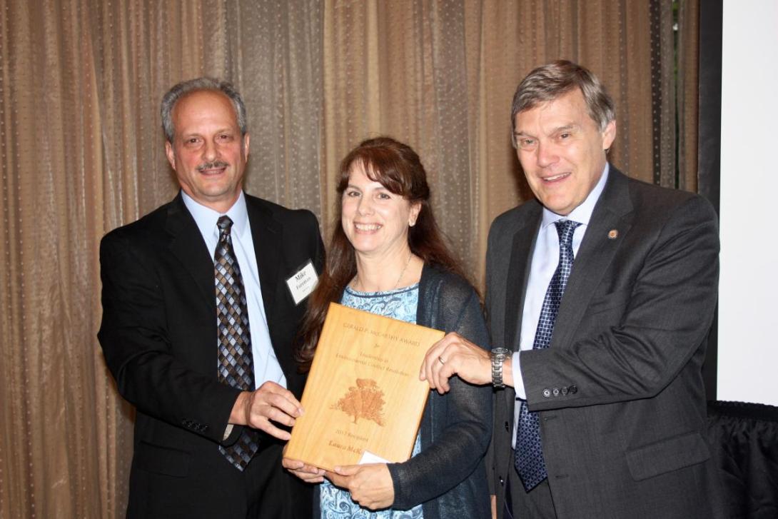 Laura McKay receives an award from Mike Foreman and David Paylor. (Woman holds plaque next two two men)